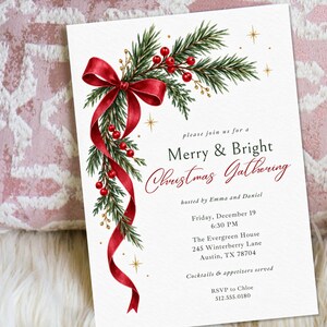 K&ouml;nnte beinhalten: Eine wei&szlig;e, rechteckige Einladungskarte mit einer Aquarellillustration aus gr&uuml;nen Tannenzweigen, roten Beeren und einem flie&szlig;enden roten Band. Der Text lautet: please join us for a Merry & Bright Christmas Gathering, hosted by Emma and Daniel.