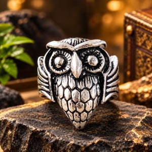 Peut inclure: Une bague en métal argenté représentant un hibou détaillé. Le hibou possède des yeux saillants, un bec pointu et des motifs de plumes texturés couvrant sa poitrine et ses ailes. Le métal présente une finition sombre et oxydée en creux.