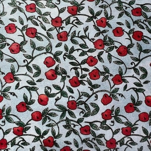 May include: A light blue fabric featuring a repeating pattern of small red apples attached to thin, dark green leafy vines. The design consists of numerous individual red fruits scattered across the light blue background, connected by dark green stems and foliage.