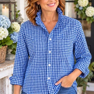 May include: A long-sleeved button-down shirt featuring a blue and white gingham check pattern, a ruffled collar, and a single chest pocket. The shirt is paired with blue denim jeans, creating a casual look with a structured collar design.