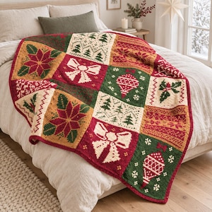 May include: A multi-colored knit blanket featuring a patchwork design with holiday-themed motifs including poinsettias, bows, ornaments, holly, and pine trees in shades of red, green, cream, and gold, arranged in a grid pattern across the fabric.