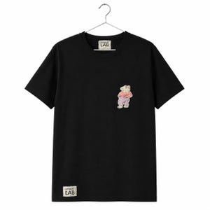 Op de afbeelding: Een zwart t-shirt met korte mouwen en een kleine afbeelding van een staande capibara in een roze shirt en paarse broek op de borst. Het shirt heeft een wit rechthoekig label met de tekst OFFBEAT LAB bij de hals en de onderzoom.