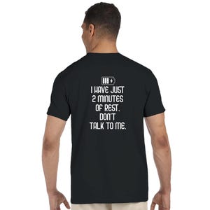 Könnte beinhalten: Ein schwarzes Kurzarm-T-Shirt mit einer weißen Grafik auf der Rückseite. Die Grafik zeigt ein Batteriesymbol und den Text: I HAVE JUST 2 MINUTES OF REST. DON'T TALK TO ME. Das T-Shirt hat einen Rundhalsausschnitt und eine Standardpassform.