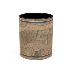 May include: A cylindrical ceramic mug featuring a vintage, sepia-toned map of New York City wrapped around the exterior. The mug has a solid black interior and a black rim. The map displays detailed street layouts, water bodies, and land plots.