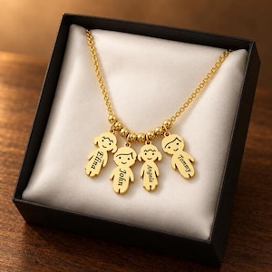 May include: A gold-toned necklace featuring four dangling charms shaped like stylized children. Each charm is engraved with a name: Elina, John, Angela, and Tommy. The chain is accented with small gold-toned beads between the charms.
