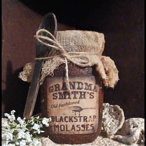May include: A rustic brown glass jar with a burlap lid and twine tied around it. The jar has a label that reads "Grandma Smith's Old Fashioned Blackstrap Molasses". A wooden spoon is tied to the jar with twine.