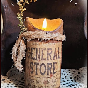 May include: A rustic candle with a warm glow, featuring a cylindrical design with a vintage "General Store" label. The candle is adorned with twine and a sprig of greenery, creating a cozy, antique aesthetic.