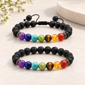 Puede incluir: Dos pulseras de cuentas con piedras de lava negra porosas y una serie de siete cuentas de piedras preciosas lisas y multicolores en morado, azul, turquesa, verde, marrón, amarillo y rojo, con pequeños espaciadores de metal plateado.