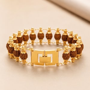 May include: A gold-toned bracelet featuring a series of brown, textured, spherical beads. Each bead is capped with gold-toned metal accents and connected by gold-toned metal links. The bracelet is secured with a rectangular gold-toned metal clasp.