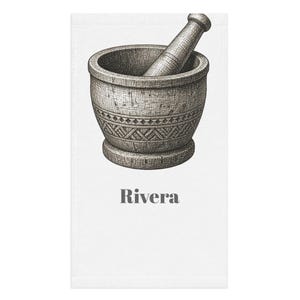 May include: A white rectangular towel featuring a detailed black and grey ink-style illustration of a mortar and pestle with geometric patterns on the base. The word Rivera is printed in a bold, dark grey serif font centered below the illustration.