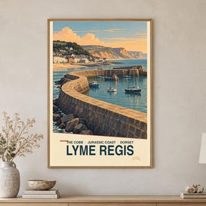 May include: A vertical wall art print featuring a scenic illustration of The Cobb in Lyme Regis, Dorset, on the Jurassic Coast. The image depicts a stone harbour wall curving into calm blue water with several small boats and a coastal town.