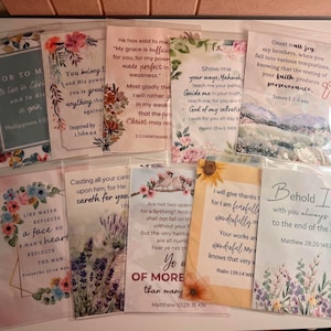 May include: A collection of ten rectangular cards, each enclosed in a clear plastic sleeve, featuring various floral illustrations and printed Bible verses. The designs include colorful flowers, lavender, birds, and landscapes with text in diverse fonts.