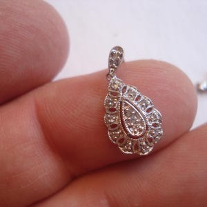 May include: A silver pendant with a teardrop-shaped design, featuring a cluster of small diamonds in the center.