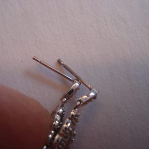 May include: Silver earring with a decorative design and a post and back closure.