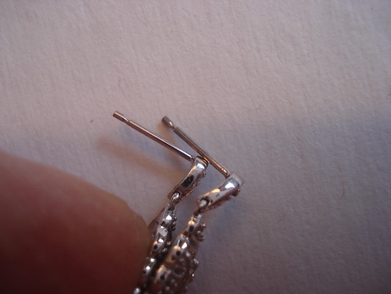 May include: Silver earring with a decorative design and a post and back closure.