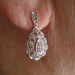 May include: A silver teardrop-shaped earring with a cluster of small clear stones.