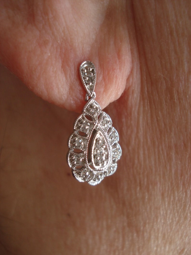 May include: A silver teardrop-shaped earring with a cluster of small clear stones.