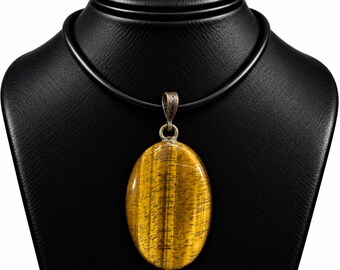 Könnte beinhalten: Ein ovaler Tigerauge-Edelsteinanhänger mit einer polierten, goldbraunen, schimmernden Oberfläche und dunklen vertikalen Streifen. Der Stein hängt an einer schlichten, dunklen Metallöse an einer glatten, schwarzen, runden Kordelkette.