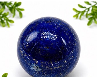 Könnte beinhalten: Eine polierte Lapis-Lazuli-Kugel in tiefem Königsblau mit natürlichen goldenen Pyrit-Einschlüssen und weißen Calcit-Adern, die über die glatte, abgerundete Oberfläche verteilt sind und ein markantes mineralisches Muster bilden.