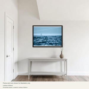 Könnte beinhalten: Ein gerahmter horizontaler Wandkunstdruck, der einen dunkelblauen Ozean mit unruhigen Wellen unter einem hellblauen Himmel zeigt, wobei ein kleines Segelboot am fernen Horizont zu sehen ist. Das Kunstwerk befindet sich in einem schwarzen Rahmen.