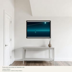 Könnte beinhalten: Ein gerahmter horizontaler Wandkunstdruck mit einer dunklen, blaugrünen Ozeanszene bei Nacht. Ein kleines Segelboot ist am Horizont unter einem hellen Vollmond zentriert. Das Kunstwerk befindet sich in einem schwarzen Rahmen an einer weißen Wand über einem Konsolentisch.
