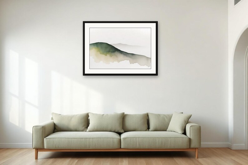 May include: A framed horizontal wall art print featuring a watercolour landscape painting of a single rolling hill in shades of muted green and beige against a white background, displayed in a simple black frame with a white mat border.