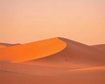 May include: A vast desert landscape featuring a large, smooth sand dune with a sharp, curved ridge. The scene is illuminated by soft, warm golden light, creating a gradient of orange and peach tones across the undulating sandy terrain.