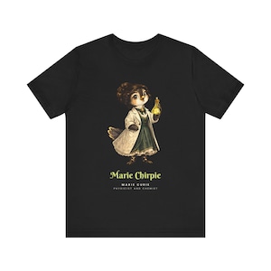 May include: A black t-shirt featuring a graphic of a bird dressed in a white lab coat and dark dress, holding a yellow glowing flask. Below the graphic, the text reads: Marie Chirpie, MARIE CURIE, PHYSICIST AND CHEMIST in yellow and white lettering.