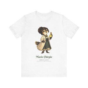 May include: A white t-shirt featuring a graphic of a bird dressed in a lab coat and dark dress, holding a glowing yellow flask. Below the illustration, the text reads Marie Chirpie, MARIE CURIE, PHYSICIST AND CHEMIST in dark green lettering.