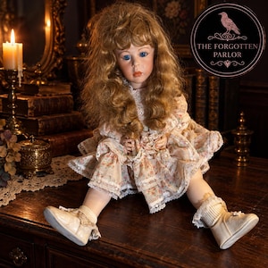 Peut inclure: Une poupée en porcelaine aux longs cheveux bruns ondulés et aux yeux bleus, vêtue d'une robe crème à motif floral avec des bordures en dentelle. La poupée porte des chaussures crème assorties avec des chaussettes à volants. Logo THE FORGOTTEN PARLOR.