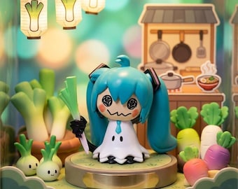 Puede incluir: Una figura de pelo azul verdoso con vestido blanco y expresión mareada que sostiene un puerro verde. La figura se alza sobre una base circular rodeada de verduras en miniatura, incluyendo puerros, rábanos y zanahorias, bajo farolillos.