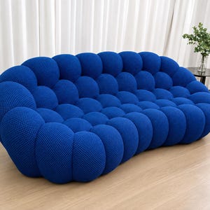 May include: A deep blue sofa featuring a distinctive bubble-like, tufted texture across its entire surface. The furniture piece has a curved, rounded silhouette with a low back and integrated armrests, upholstered in a textured fabric material.