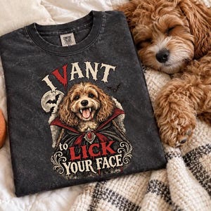Op de afbeelding: Een antracietgrijs acid-wash T-shirt met een afbeelding van een hond verkleed als vampier met een rood gevoerde cape. De tekst luidt I VANT to LICK YOUR FACE in witte en rode letters, vergezeld van een illustratie van een maan en vleermuizen.