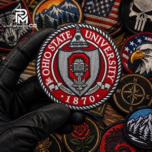 May include: A circular embroidered patch featuring the Ohio State University seal in red, white, and black. The design includes a central shield with an open book, a leaf, and the text OHIO STATE UNIVERSITY 1870 with the Latin motto DISCIPLINA CIVITATEM.