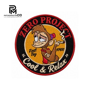 May include: A circular embroidered patch featuring a brown cartoon monkey with a red shirt, holding a smoking cigarette. The design includes the text ZERO PROJECT, First Try, 97410, and Cool & Relax, set against a yellow center and black border.