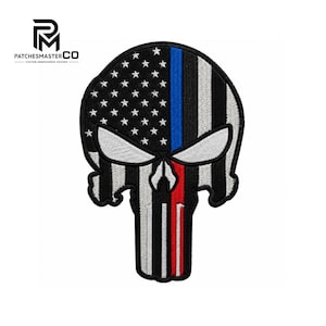 May include: An embroidered patch shaped like a skull, featuring a black and white American flag pattern with a vertical blue stripe on the left side and a vertical red stripe on the right side, with white stars on a black background at the top.