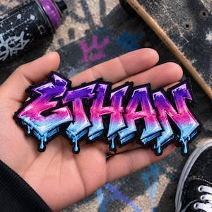 May include: An embroidered patch featuring the name ETHAN in a graffiti-style font. The letters transition from a vibrant pink at the top to a bright blue at the bottom, with a black outline and a dripping effect at the base of each letter.