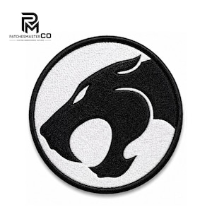 Puede incluir: Un parche bordado circular que presenta una silueta de cabeza de felino estilizada en negro centrada sobre un fondo blanco, rodeada por un borde negro grueso. El logotipo de PATCHESMASTERCO es visible en la esquina superior izquierda.