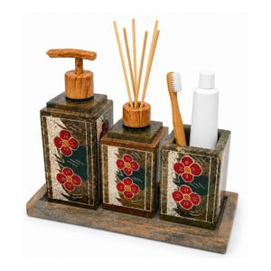 May include: A bathroom accessory set featuring a rectangular soap dispenser, a reed diffuser, and a toothbrush holder on a matching tray. Each piece is made of dark green stone with red flower motifs and light wood-toned accents.