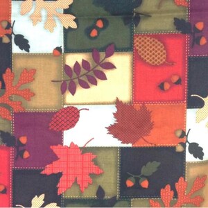 May include: A fabric featuring a patchwork grid of squares in shades of red, orange, yellow, green, purple, and white. The pattern is decorated with various autumn leaves, including maple and oak shapes, alongside small acorns and textured pinecones.