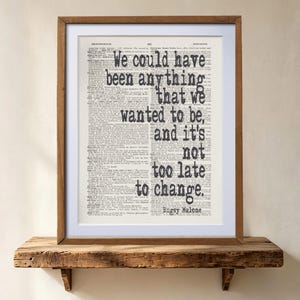 Può includere: Una stampa incorniciata con uno sfondo di pagina di dizionario e il testo nero: We could have been anything that we wanted to be, and it's not too late to change. Bugsy Malone. La cornice è in legno di tonalità media con un bordo bianco.
