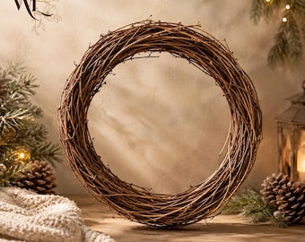 May include: A circular wreath constructed from thin, intertwined brown twigs. The wreath features a natural, woody texture with a hollow center, showcasing a simple, unadorned design made from dried natural branches arranged in a continuous loop.