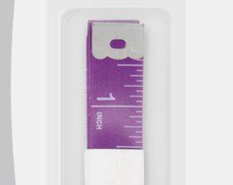May include: A purple Dritz 120 inch quilter's flip tape measure in its original packaging. The tape features white measurement markings and numbers, with a metal end tab. The packaging displays the text 120 inch Quilter's Flip Tape Measure.