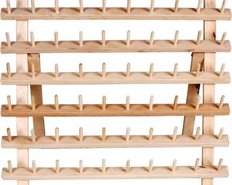 May include: A light-colored wooden thread rack featuring six horizontal bars, each equipped with eleven evenly spaced vertical pegs. The structure is supported by two angled side supports, creating a freestanding display for organizing spools.