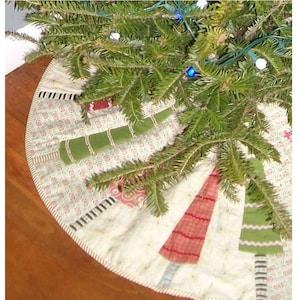 May include: A circular fabric Christmas tree skirt featuring a cream-colored background with a repeating pattern of small shapes. The skirt is decorated with alternating appliqued tree shapes in shades of green and red, accented with striped trunks.