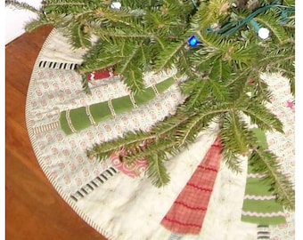 May include: A circular fabric Christmas tree skirt featuring a cream-colored background with a repeating pattern of small shapes. The skirt is decorated with alternating appliqued tree shapes in shades of green and red, accented with striped trunks.