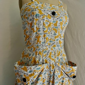K&ouml;nnte beinhalten: Vintage Kleid mit gelbem, wei&szlig;em und schwarzem Muster. Es hat ein einzigartiges Muster aus Noten und abstrakten Formen. Quadratischer Ausschnitt, zwei gro&szlig;e Taschen und schwarze Kn&ouml;pfe. Ma&szlig;e sind nicht verf&uuml;gbar.