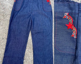 May include: A pair of dark blue denim pants with red star embroidery on the pockets. The pants have a high waist and a straight leg.