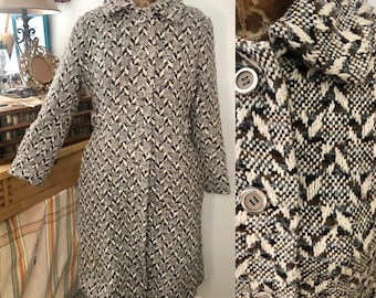 May include: A long-sleeved, black and white patterned coat with a brown accent. The coat has a collar and button closure.
