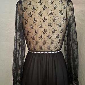 May include: Black vintage dress with a high neckline and long sleeves. The bodice is sheer black lace with a floral pattern over a nude lining. The waist is accented with a white ribbon and the skirt is a solid black fabric.